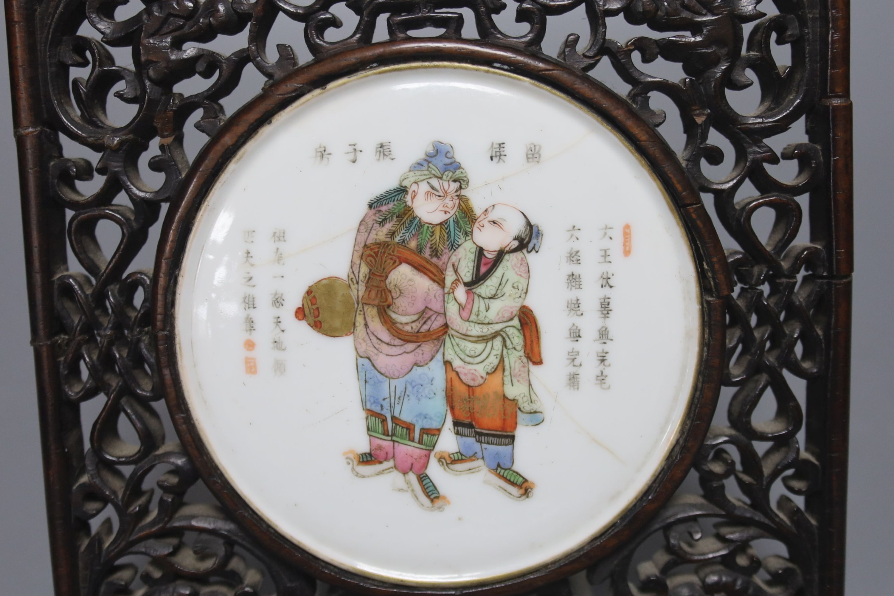 A 19th century Chinese famille rose circular plaque or cover, inset into a wood surround, cracks 15cm sq